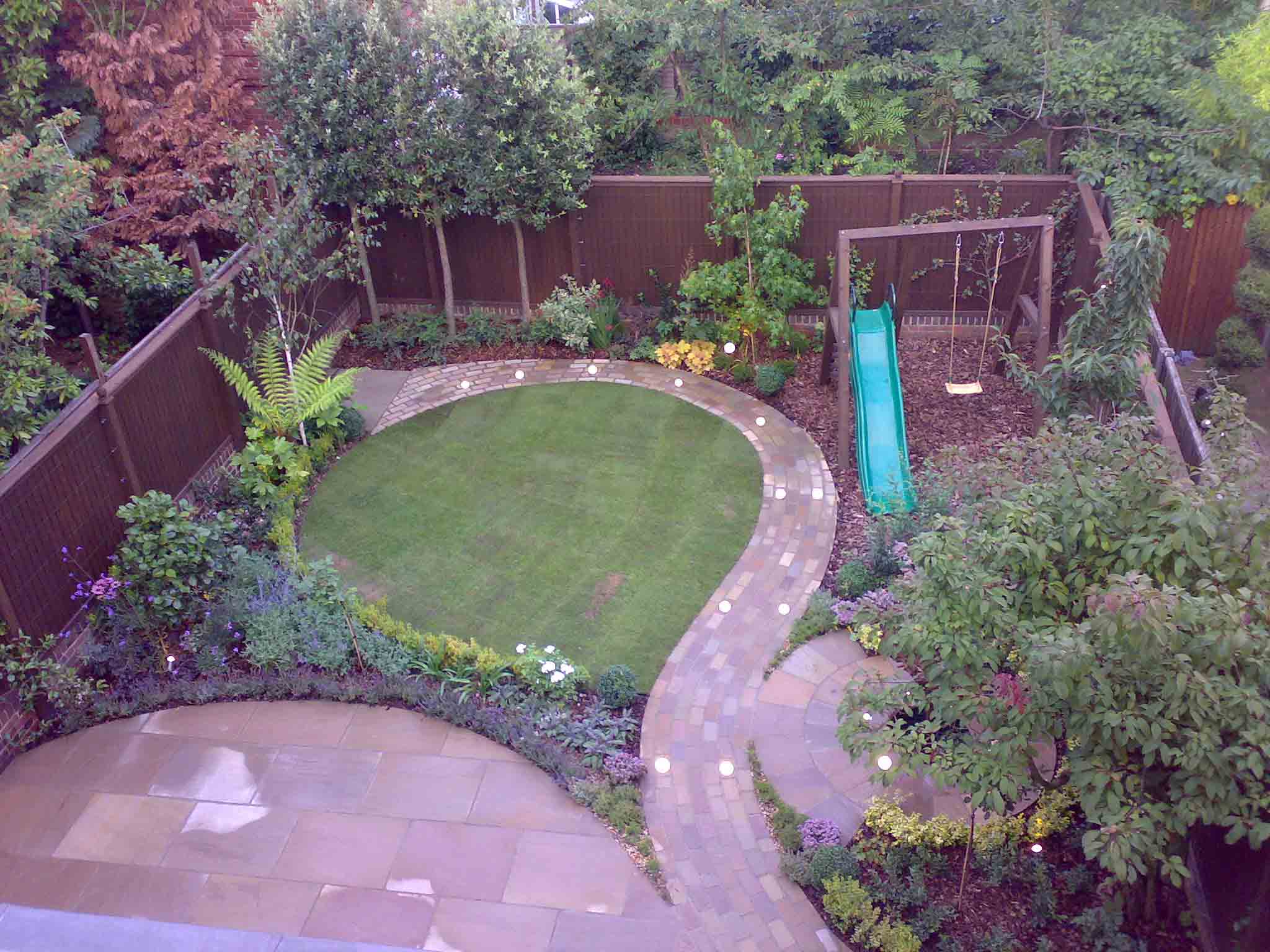 Office staff garden courtyard with table chairs and modern furnishings and clipped bay trees and large umbrella canopies
